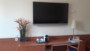 a television on a wall with a vase of flowers on a desk at Hotel RH Sorolla Centro in Valencia