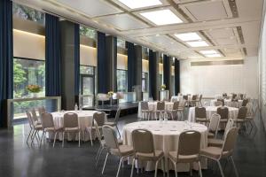 a banquet hall with white tables and chairs and windows at Excelsior Hotel Gallia, a Luxury Collection Hotel, Milan in Milan