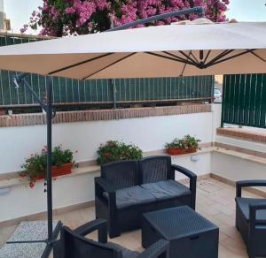 a patio with an umbrella and a couch and tables at Riviera AlbaChiara B&b in Anzio