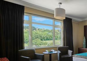 a room with a window with a chair and a table at Grand Jersey Hotel and Spa in Saint Helier Jersey
