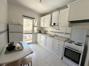 a kitchen with white appliances and a table in it at Edificio Canoa in Armação de Pêra