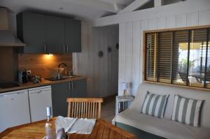 a kitchen with a table and a couch in a room at La Cabane 14 climatisée - Escapade sur le Bassin d'Arcachon - Terrasse & Nature in Lanton