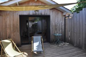 a wooden deck with two chairs and a door at La Cabane 14 climatisée - Escapade sur le Bassin d'Arcachon - Terrasse & Nature in Lanton