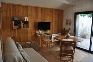 a living room with a table and a television at La Cabane 14 climatisée - Escapade sur le Bassin d'Arcachon - Terrasse & Nature in Lanton