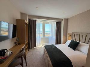 a hotel room with a bed and a desk and a window at Emerald Tide Hotel - Blackpool in Blackpool