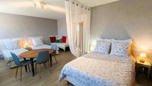 a bedroom with two beds and a table and chairs at Les Chambres de Grangette in Thury