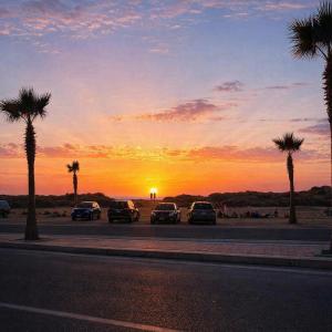 a group of cars parked in a parking lot with a sunset at Villa L'initiale in Oualidia
