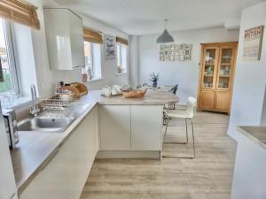 a kitchen with white cabinets and a sink at Beach Break Aberavon Holiday Home by the Sea in Port Talbot