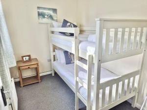 a bedroom with two bunk beds and a table at Beach Break Aberavon Holiday Home by the Sea in Port Talbot