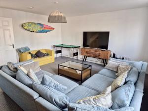 a living room with a couch and a ping pong table at Beach Break Aberavon Holiday Home by the Sea in Port Talbot