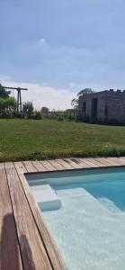 a swimming pool with a wooden deck and a field at Chambre d'hôte Escale piscine in Ghislenghien