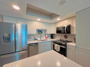 a kitchen with white cabinets and a stainless steel refrigerator at Vacation Villas #432 - Beachfront Condo in Fort Myers Beach +11 photos