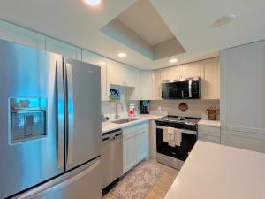 a kitchen with white cabinets and a stainless steel refrigerator at Vacation Villas #432 - Beachfront Condo in Fort Myers Beach
