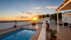 a villa with a swimming pool and a sunset at La Ventana al Mar in Güime