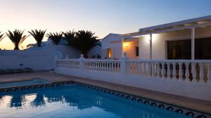 a villa with a swimming pool in front of a house at La Ventana al Mar in Güime