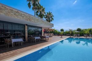 a swimming pool with tables and chairs next to a building at Laristone Suite Spa Hotel in Antalya