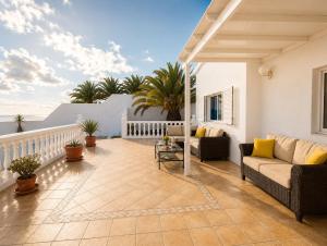 a patio with a couch and chairs on a balcony at La Ventana al Mar in Güime +33 photos