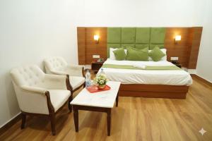 a hotel room with a bed and two chairs and a table at Hotel Grand Royal Sandhu in Amritsar +13 photos