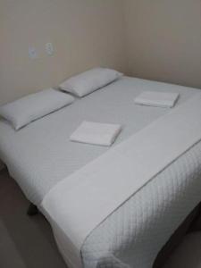 ein großes weißes Bett mit weißen Laken und Kissen in der Unterkunft Hotel Prata Express in Pratânia