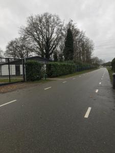 an empty road with a fence and trees on the side at B&B An de N35 in Zwolle