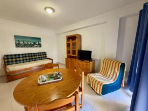a living room with a wooden table and a bed at Caravela B in Armação de Pêra