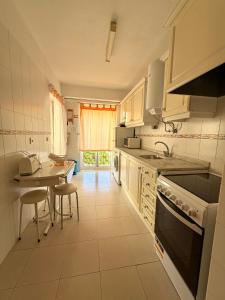 a kitchen with white cabinets and a table and chairs at Caravela B in Armação de Pêra