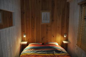 a bedroom with wooden walls and a bed with two lights at La Cabane 14 climatisée - Escapade sur le Bassin d'Arcachon - Terrasse & Nature in Lanton