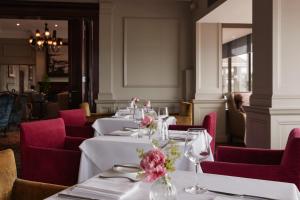 a dining room with white tables and red chairs at Grand Jersey Hotel and Spa in Saint Helier Jersey