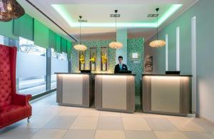a lobby of a hotel with a man sitting at a counter at Leonardo Hotel Munich City South in Munich