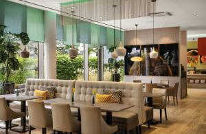 a dining room with tables and chairs and windows at Leonardo Hotel Munich City South in Munich