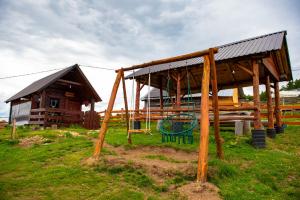 a wooden pavilion with a playground in front of a building at Eko Kamp Garcevic in Plav