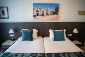 a bedroom with two beds with blue pillows at Mikes Kanarium City Hotel in Larnaca +42 photos