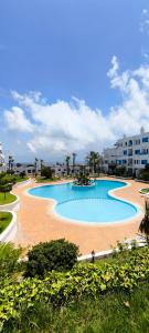 a large swimming pool with palm trees and buildings at Magnifique appartement de trois chambres, Résidence Kabila Vista in M'diq