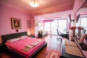 Holidays Pelion في نيا أنخيالوس: غرفة نوم وردية مع سرير وغرفة معيشة