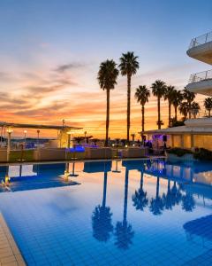 a pool with palm trees and a sunset in the background at Hotel Gli Dei in Pozzuoli