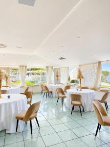 a restaurant with white tables and chairs and windows at Hotel Gli Dei in Pozzuoli