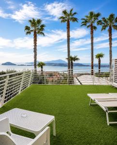 a patio with palm trees and a lawn at Hotel Gli Dei in Pozzuoli