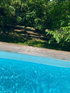 a pool of blue water with a picnic table and trees at Gîtes Les Perouilles - La Roulotte Climatisée avec Jacuzzi et Piscine Hors sol de Josépha in Puymiclan