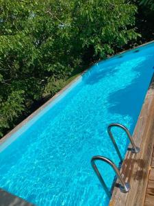a large blue swimming pool next to some trees at Gîtes Les Perouilles - La Roulotte Climatisée avec Jacuzzi et Piscine Hors sol de Josépha in Puymiclan +23 photos