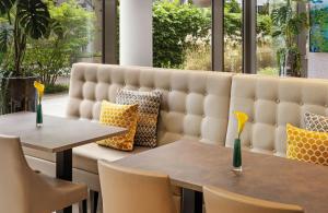 two tables and chairs in a room with windows at Leonardo Hotel Munich City South in Munich +41 photos