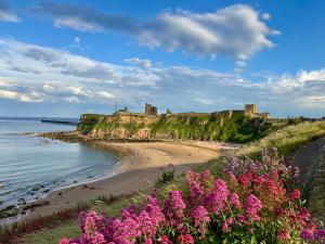 a view of a beach with a castle in the background at Victoria Cottage, Cullercoats in Cullercoats +38 photos