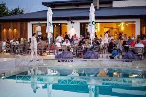 a group of people sitting at a restaurant with a pool at Maria village resort in Pavel Banya
