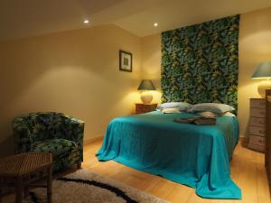 a bedroom with a blue bed and a chair at MAISON d HOTES in May-sur-Orne