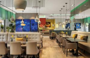 a restaurant with tables and chairs and a cafeteria at Leonardo Hotel Munich City South in Munich