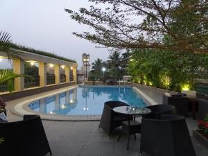 a swimming pool with a table and chairs next to a building at Misty Meadows, Lonavala in Lonavala