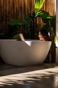 a woman sitting in a bath tub with a book at Nayma Villas in General Luna