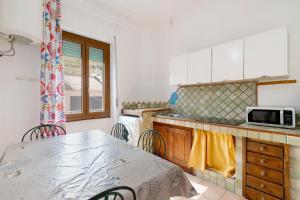 a kitchen with a table and a microwave in it at Casa Silvia trilo calagavetta in La Maddalena