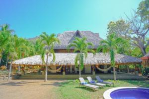 a resort with palm trees and chairs and a building at Las Golondrinas KM59 in Taquillo