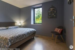 a bedroom with a bed and a window and a chair at Le Moulin de Commagny in Moulins-Engilbert