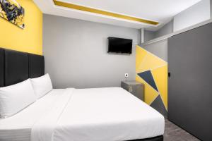 a bedroom with a white bed and a tv at Hotel Metro Lodge Xpress in Durban